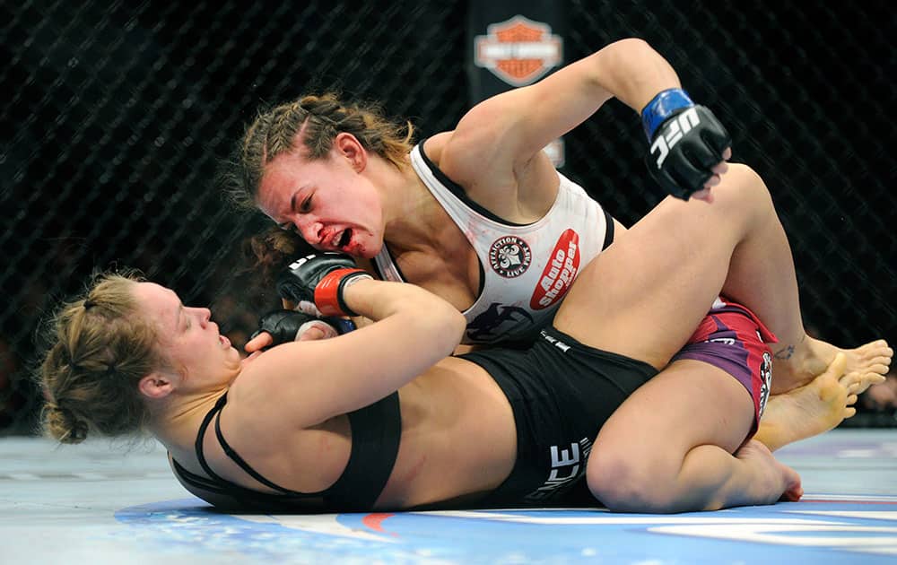 Miesha Tate, top, of Yakima, Wash., punches to Ronda Rousey of Venice, Calif., during the UFC 168 mixed martial arts middleweight championship bout during the UFC 168 mixed martial arts women`s bantamweight title fight in Las Vegas. Rousey won by a third round tap out.