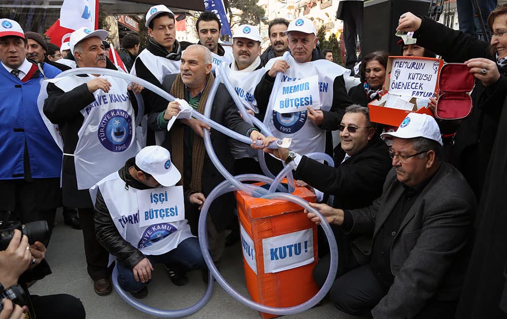 People hold hose-pipes which in Turkey has come to symbolize syphoning of public funds, as they shout