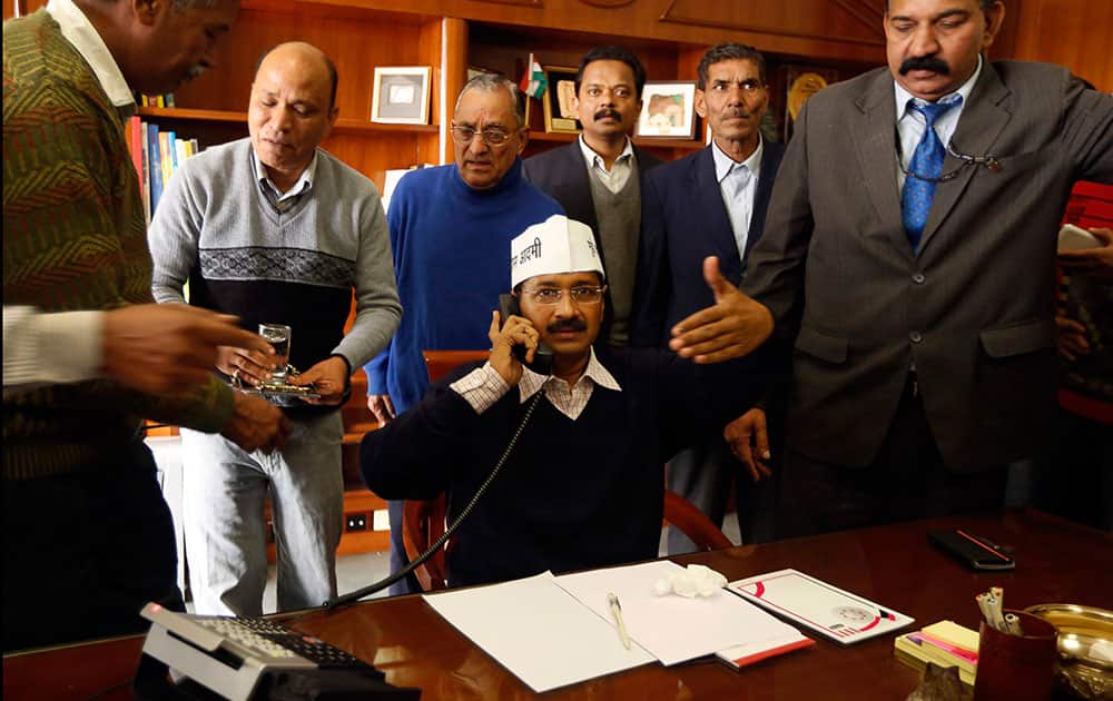 Aam Aadmi Party, or Common Man`s Party, leader Arvind Kejriwal talks on a phone as he is seated to assume the office of the Chief Minister of Delhi in New Delhi.
