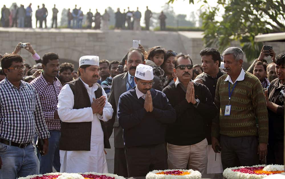 Aam Aadmi Party, or Common Man`s Party, leader Arvind Kejriwal, center, pays respect at the memorial of Mahatma Gandhi after being sworn in as the chief minister of Delhi, in New Delhi.