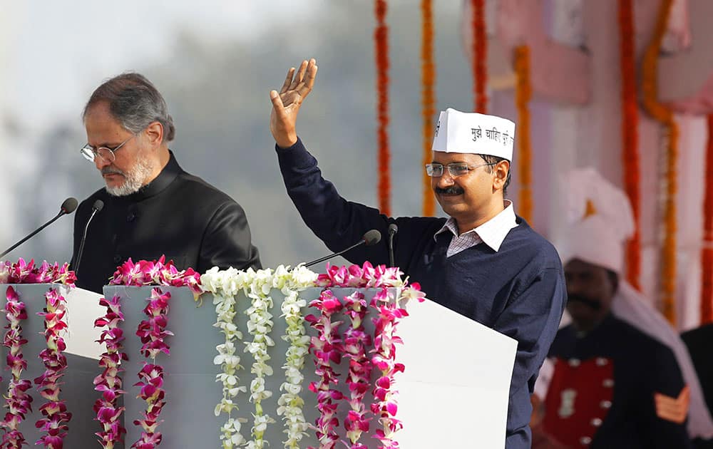 Aam Aadmi Party, or Common Man`s Party, leader Arvind Kejriwal, right, waves to the crowd as he arrives to be sworn-in as chief minister of Delhi in New Delhi.