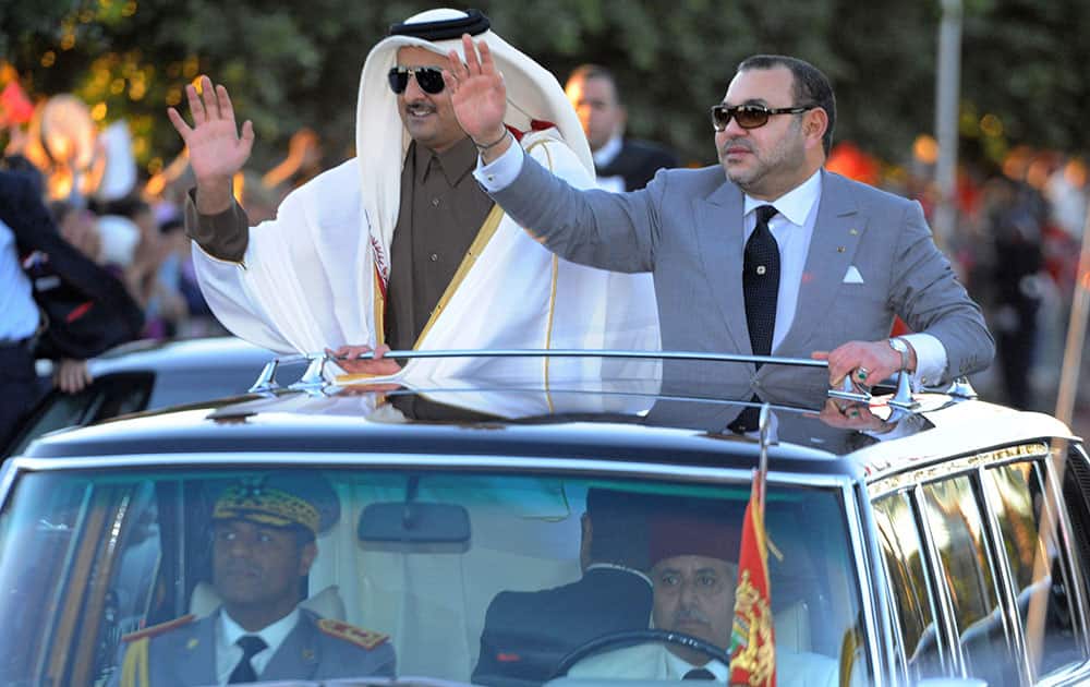 This photo provided by the Moroccan News Agency (MAP), Moroccan King Mohammed VI, right, and The Emir of Qatar, Sheikh Tamim bin Hamad Al-Thani, wave as they stand in an open limousine in Marrakech, Southern Morocco.
