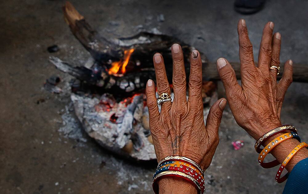 A woman warms herself in front of a bonfire in New Delhi. Large swathes of North India bore the brunt of cold wave and icy winds as temperatures dipped in several parts of the region, according to local news reports.
