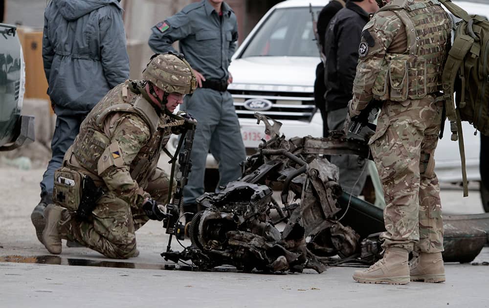 NATO forces examine the remains of a car after a suicide car bomb attack on the Jalalabad-Kabul road in Kabul, Afghanistan.