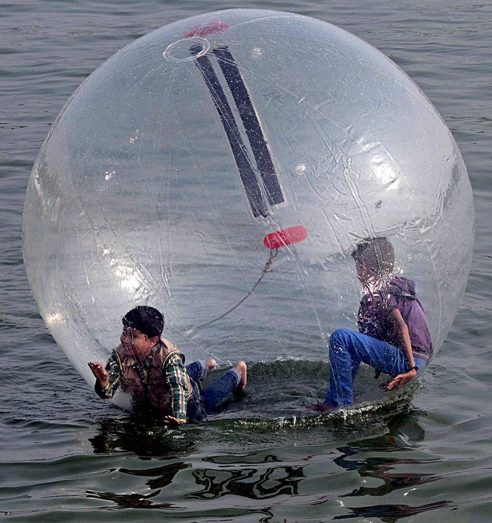 Youths enjoy a ride in floating spheres as tourists throng Kankaria lake in Ahmedabad on Thursday during one week long Kankaria Carnival.
