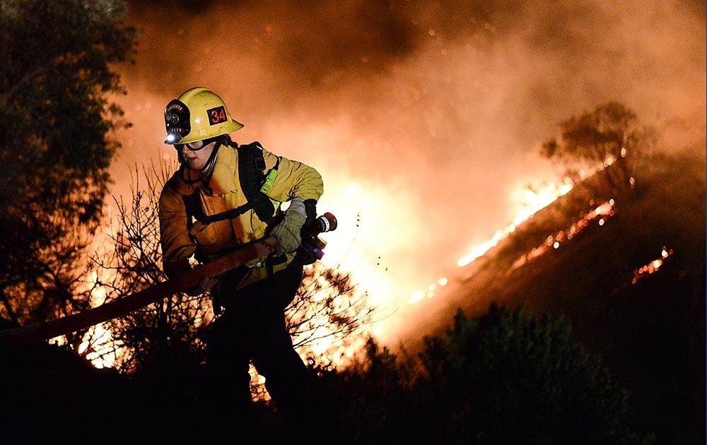 Firefighters battle a wind-driven brush fire in Simi Valley, Calif. Strong Santa Ana winds spread the fire quickly, however, firefighters gained the upper hand in several hours after an all out assault using water dropping helicopters, engines, and hand crews.