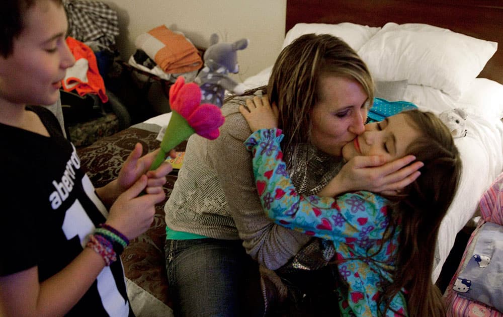 Jill Ghantous, center, kisses her daughter, Briana Ghantous, 6, at the Wingate Hotel,in Grand Blanc Township, Mich. The Ghantous family lost power on Sunday at their home in Swartz Creek due to ice storms that have left about 40,000 people in Genesee County without power. Lacking power at their home, the family opened their Christmas presents Wednesday morning at the hotel.