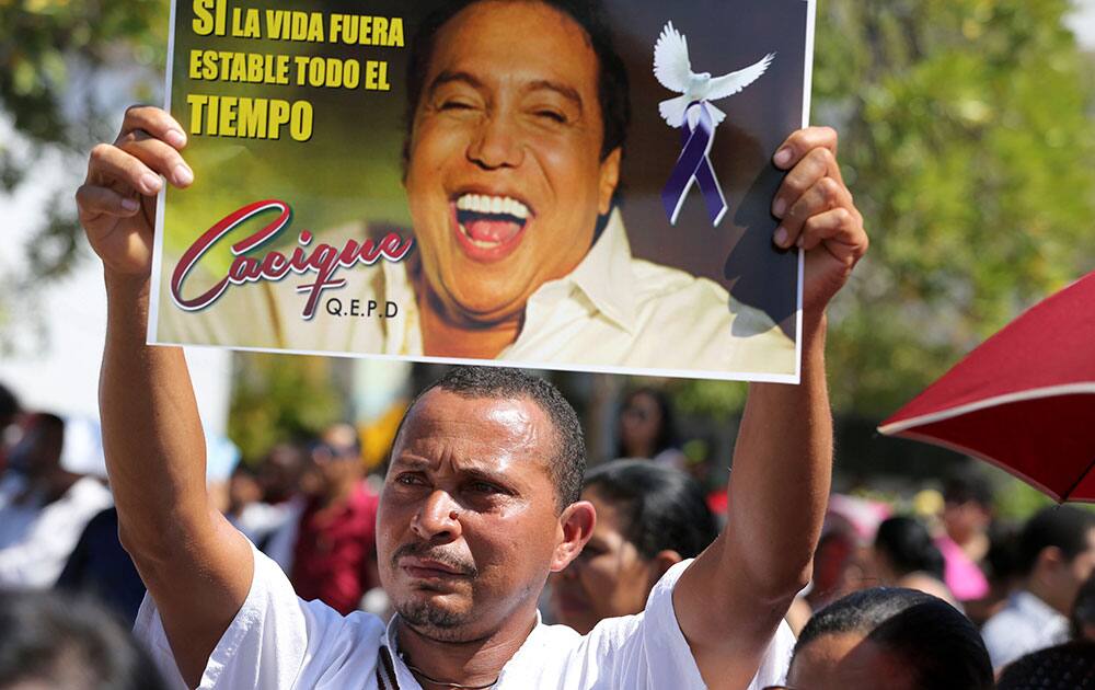 A man holds a poster of singer and composer Diomedes Diaz during his funeral mass at the main square of Valledupar, Colombia`s northern state of Cesar. Diomedes Diaz, one of the greatest performers of Colombia`s accordion vallenato music, died Sunday, Dec. 22, 2013, at age 56.