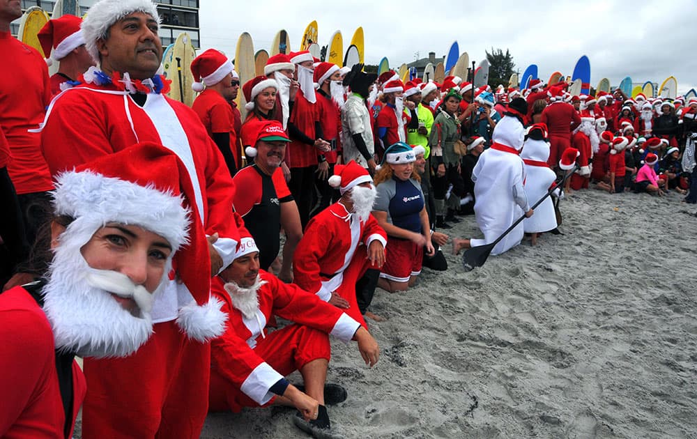 Shaylona Kirk, of Cocoa Beach, left, peeks at the camera during the photo shoot of over 210 surfers dressed as Santa Claus, elves and snowmen at the fourth annual