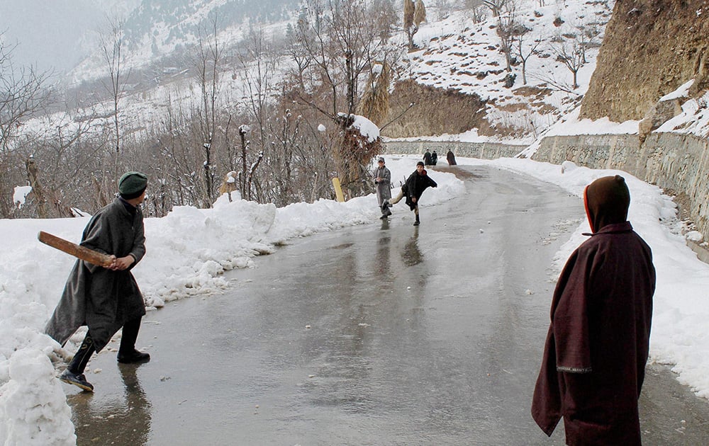 Kashmiri village boys playing cricket on snow covered road,at Famous Tourist Resort in Pahalgam.