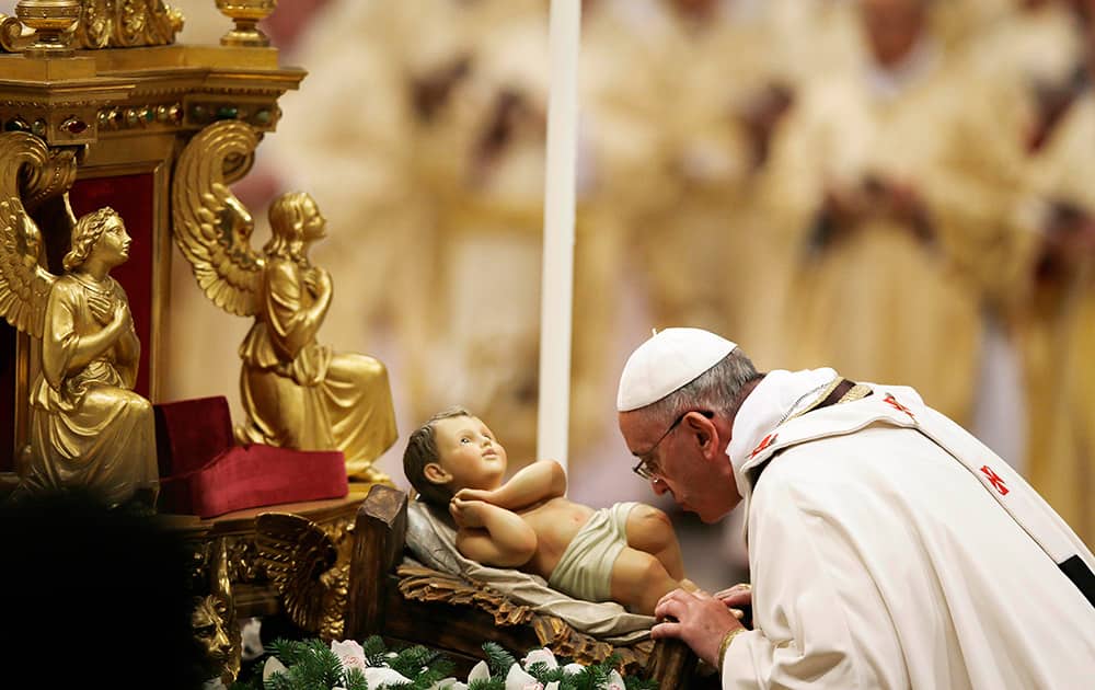 Pope Francis kisses a statue of baby Jesus as he celebrates the Christmas Eve Mass in St. Peter`s Basilica at the Vatican.
