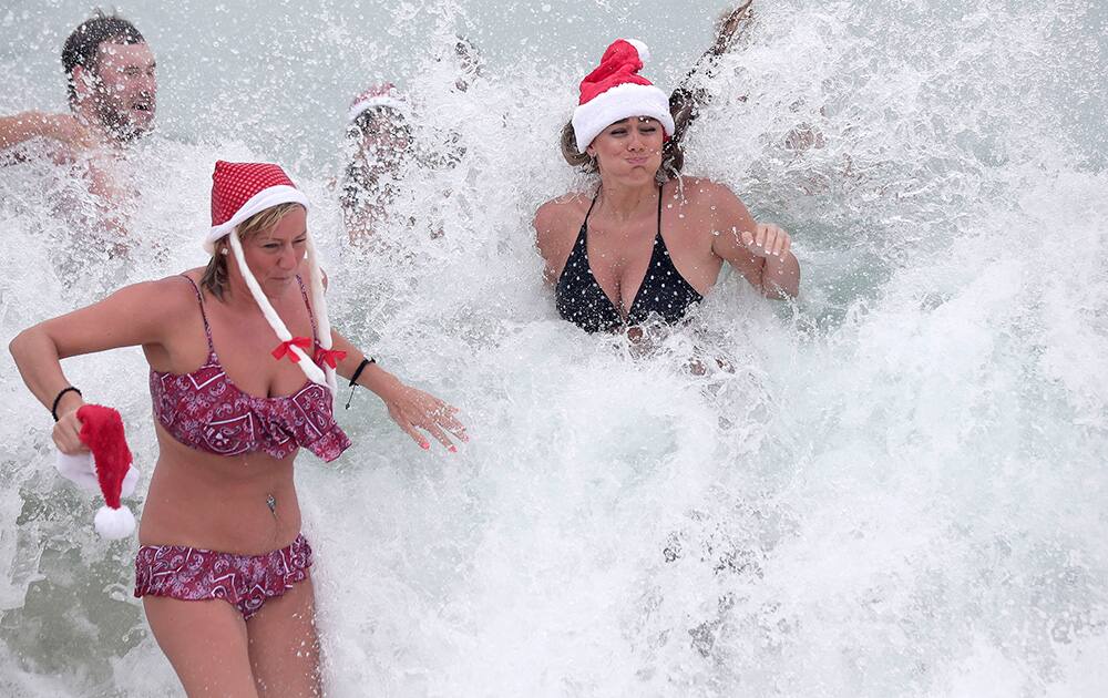 Sarah O`Grady, left, and Tanya O`Grady, both from Birmingham in the United Kingdom, get hit by a wave at Bondi Beach as they celebrate Christmas Day in Sydney.