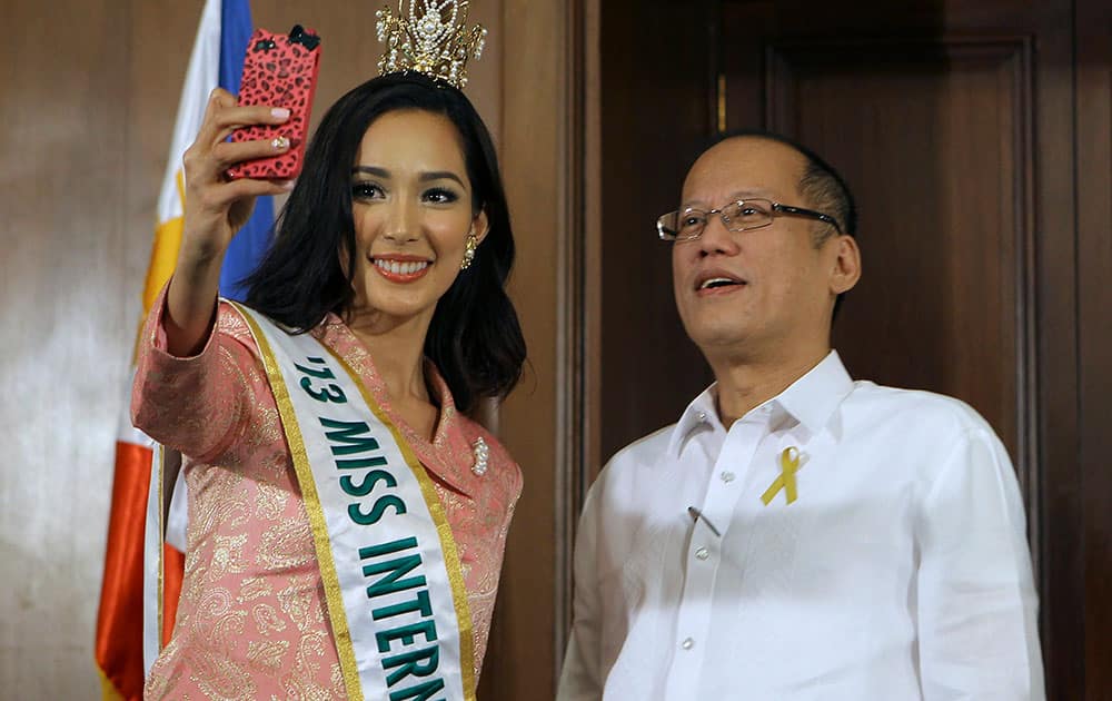 Handout photo released by the Malacanang Photo Bureau, Philippine President Benigno Aquino III, right, poses as Miss International 2013 Bea Santiago takes a photo using her smartphone camera during her courtesy call at the Malacanang Presidential Palace in Manila.