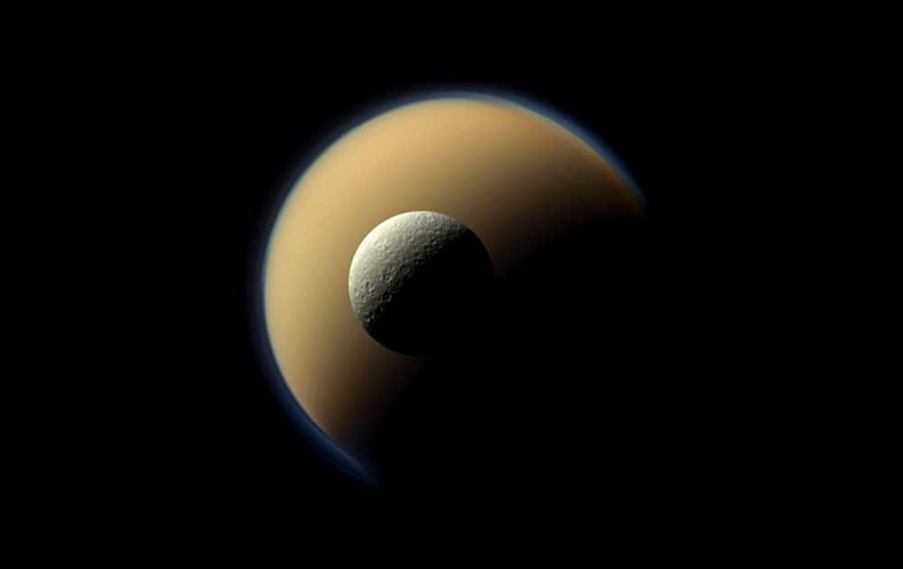 This June 16, 2011 photo provided by NASA/JPL-Caltech/Space Science Institute shows Saturn`s largest and second largest moons, Titan and Rhea, appearing to be stacked on top of each other in this true-color scene from NASA`s Cassini spacecraft. The images were taken using red, green and blue spectral filters that were combined to create this natural-color view.