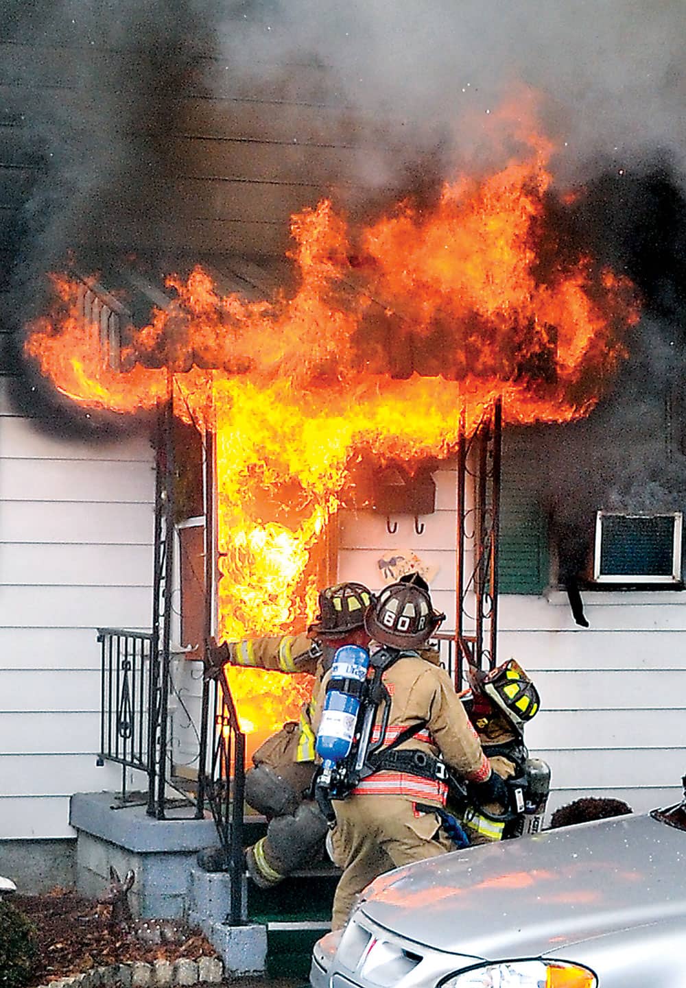 Firefighters are forced back as flames burst out the front door of 11 Cross Street in Danville, Pa.