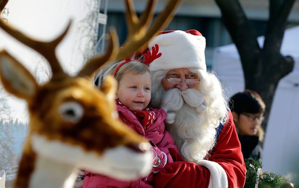 A man from Lapland, Finland dressed as Santa Claus poses with a girl for souvenir photos to celebrate Christmas in downtown of Seoul, South Korea.