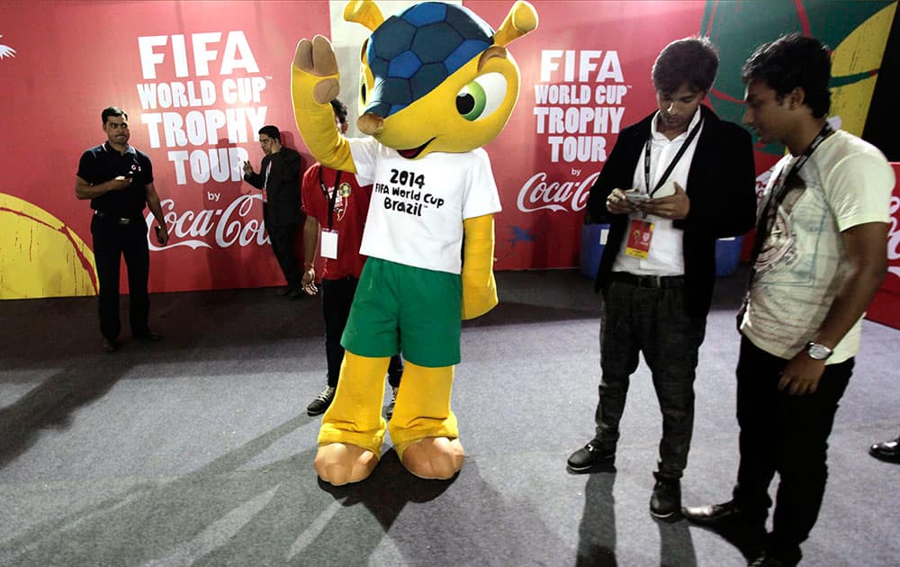 An Indian man dressed as Fuleco, mascot for the 2014 World Cup soccer tournament, greets spectators during the unveiling of the trophy for public display in Kolkata.