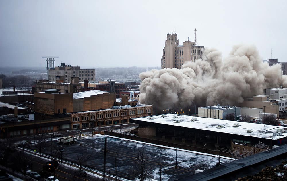 The Genesee Towers collapses on itself after demolition crews detonated charges to destroy the building on Sunday, Dec. 22, 2013 in downtown Flint, Mich.