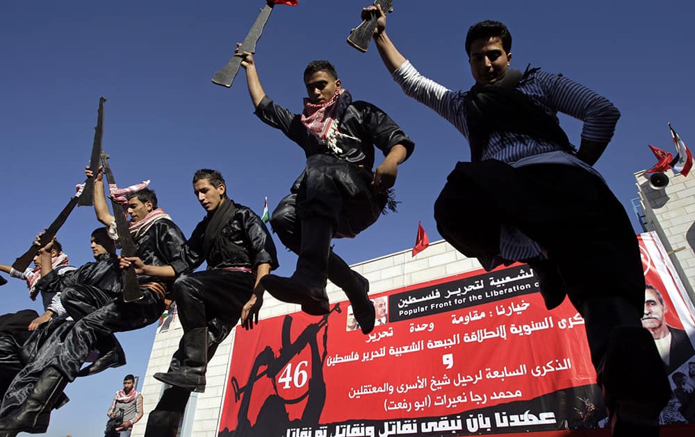 Palestinians dance the Dabka, an Arab folk line dance, with mock weapons made from wood at a rally marking the 46th anniversary of the founding of the Popular Front for the Liberation of Palestine (PFLP), in the West Bank village of Maythalun, near Jenin.
