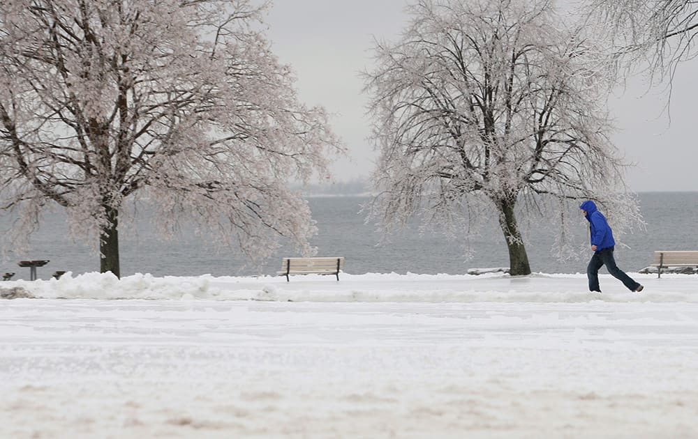 A man walks through a snow-covered park in Kingston, Ontario, Canada. A major freezing rain weather front is moving through the eastern part of Canada.
