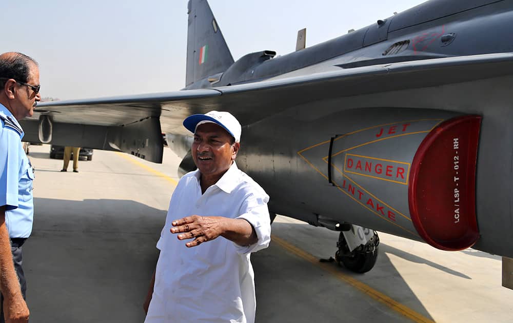 Indian Defense Minister A.K. Antony, right, gestures to media persons as Air Force chief NAK Browne walks to join him for a photo opportunity next to India`s indigenously designed and developed multirole supersonic combat aircraft Tejas after its air display at Hindustan Aeronautics Limited airport in Bangalore.