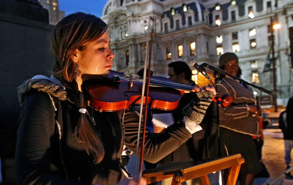 Tears stream down the face of Shandi Beardsley, as she plays her violin while the names of the homeless that have died are read over the public address system to the crowd gathered at Thomas Paine Plaza for the Homeless Memorial Day, in Philadelphia.