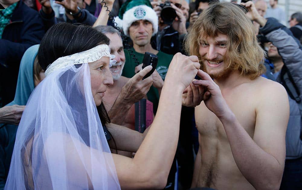 Gypsy Taub, left, places a ring on the finger of Jaymz Smith, right, during their nude wedding outside City Hall, in San Francisco.