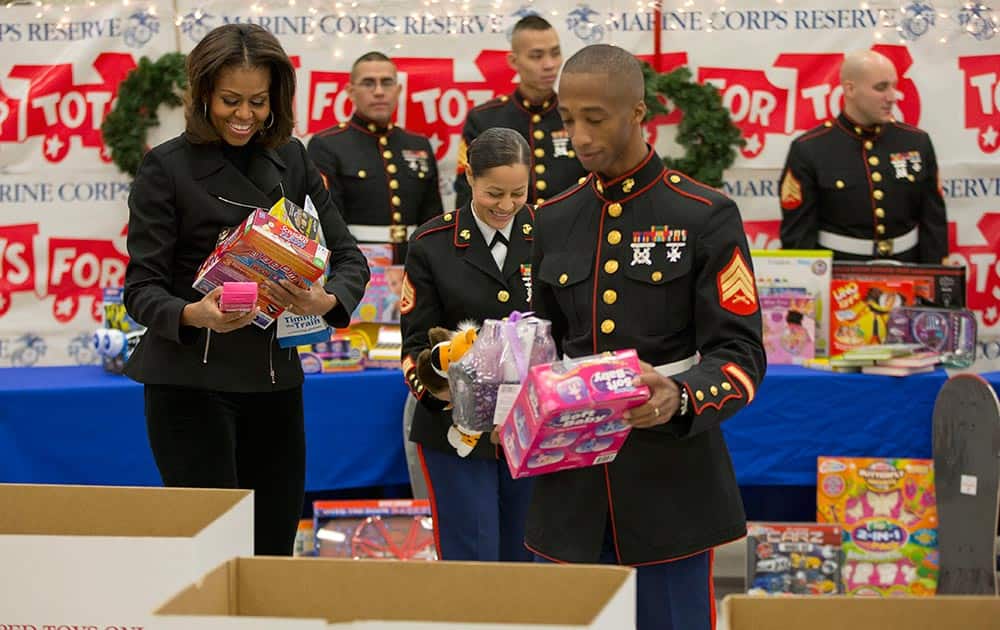 First lady Michelle Obama, left,, with the help of Staff Sgt. Catalina Milagro Perez, center, and Sgt. David Nathaniel Hayes, right, help sort toys and gifts during her visit to Joint Base Anacostia-Bolling in Washington.