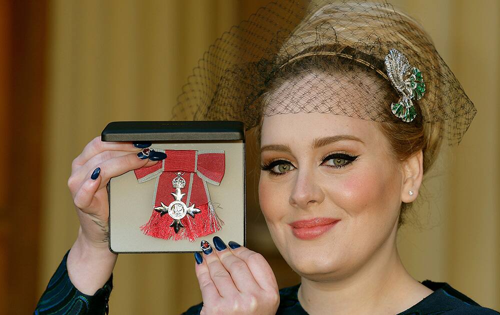 British singer Adele Adkins holds her MBE for services to music presented to her by the Prince of Wales at Buckingham Palace in London.