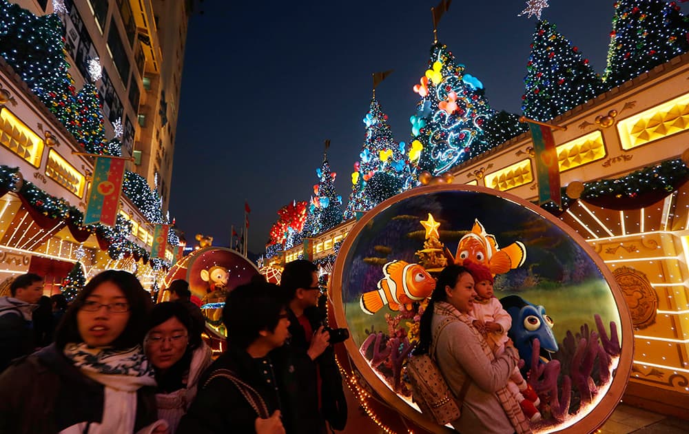 Visitors pose for photographs in front of Christmas decorations displayed in celebration of the holiday season at a shopping mall in Hong Kong.