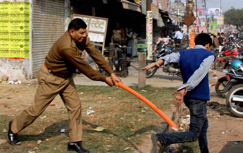 A policeman disperses students protesting against corruption in civil services in Uttar Pradesh Public Service Commission Recruitment during a chakka jaam at NH2, in Allahabad.