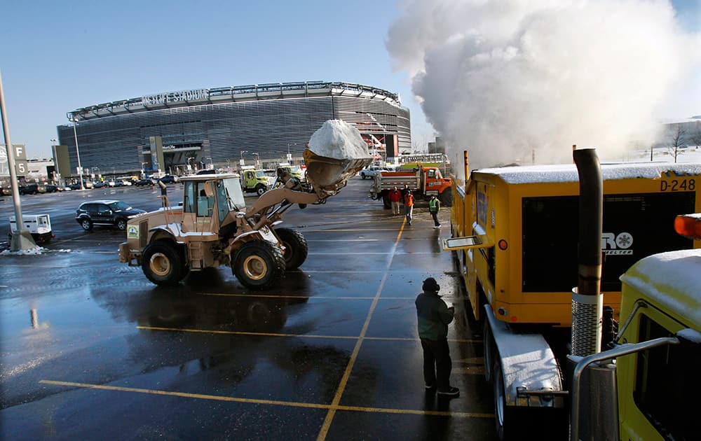 A large machinery melts snow as workers remove snow from parking lots at MetLife stadium in East Rutherford, N.J.
