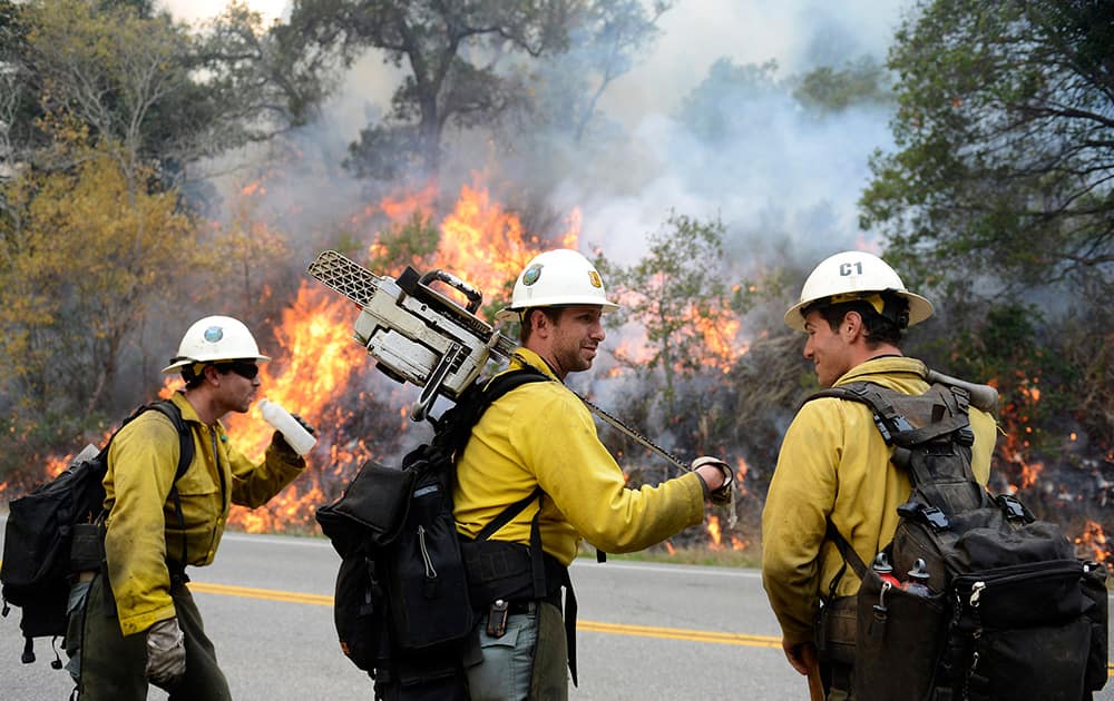 Los Padres National Forest firefighters, from left, Michael Sheppard, Tyson Navarro and Alex Woodhull take a break while lighting a backfire along Highway 1 between Pfeiffer Ridge Road and the Big Sur Station in Big Sur, Calif.