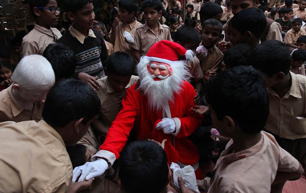 A blind child dressed as Santa Claus distributes candies during Christmas celebrations at the Devnar School for the Blind in Hyderabad.
