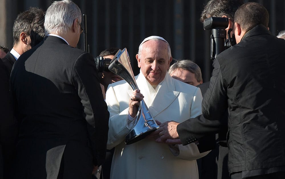 Pope Francis looks at a replica of the Argentine soccer major league`s trophy he was presented by a delegation of San Lorenzo soccer team, at the end of his weekly general audience in St. Peter`s Square at the Vatican.
