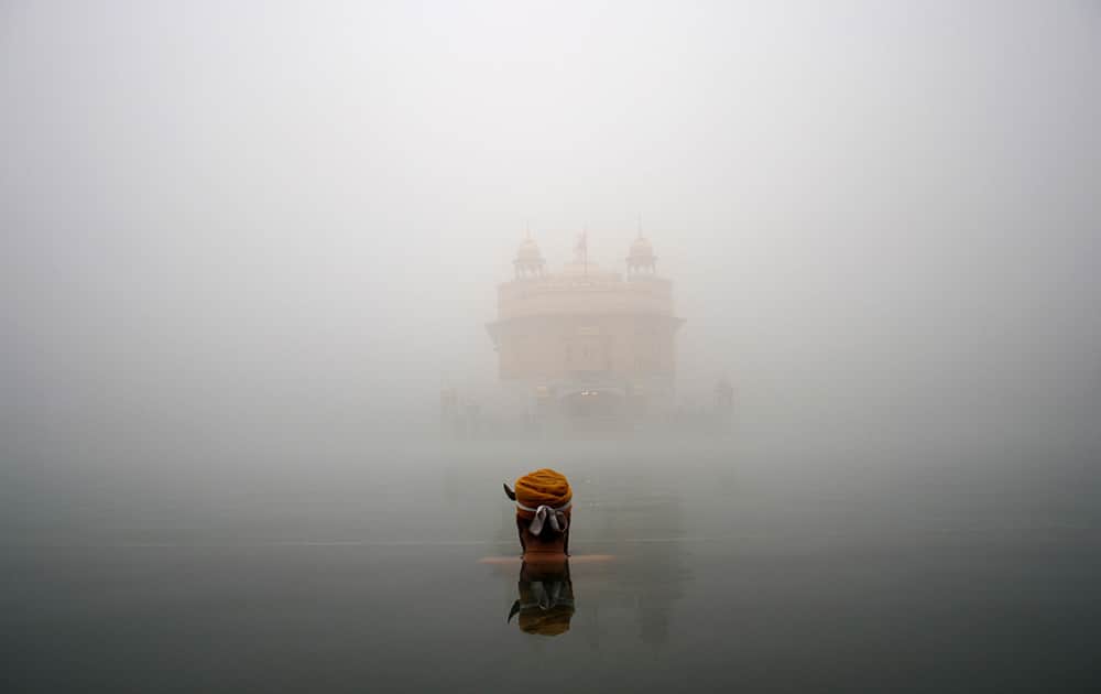 A Sikh devotee takes a holy bath in a sacred pond at the Golden Temple, the holiest Sikh shrine, amidst thick fog in Amritsar.