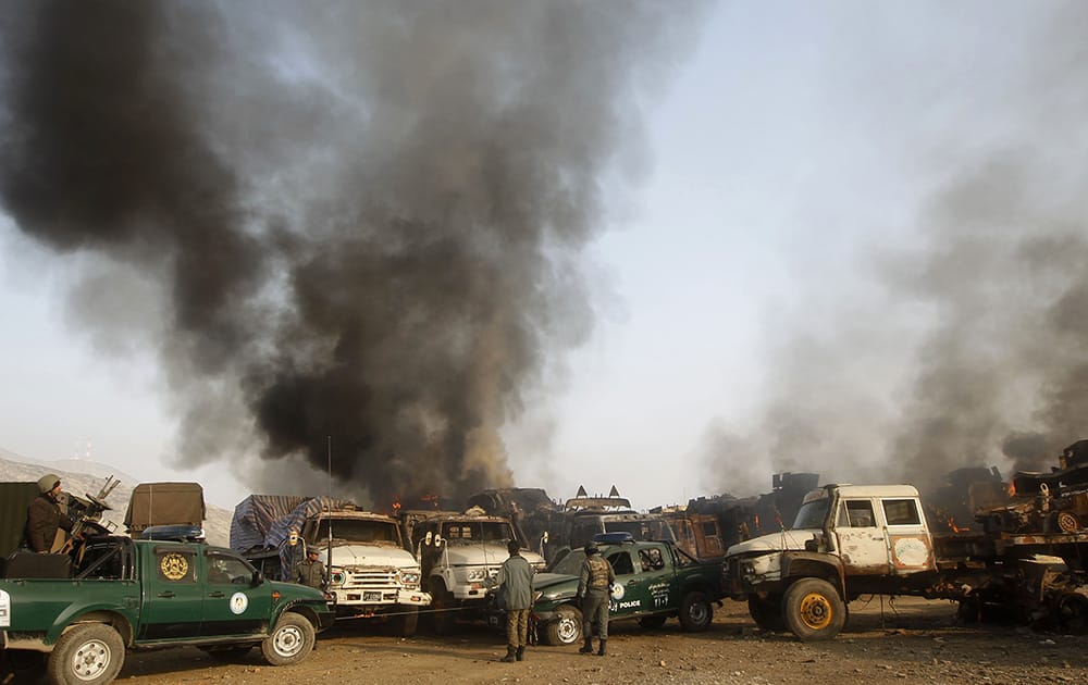 Afghan policemen stand guard near burning NATO supply trucks following an attack by militants in the Torkham area near the Pakistani Afghan border in Jalalabad province east of Kabul, Afghanistan.