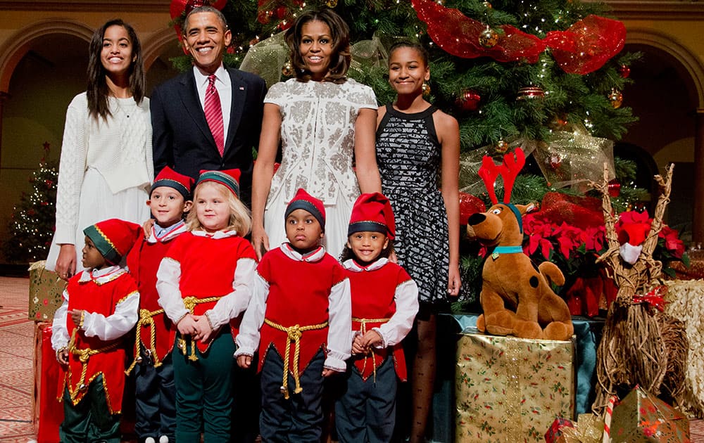 The first family, from left, Malia Obama, President Barack Obama, first lady Michelle Obama, and Sasha Obama, pose with children dressed like elves at the National Building Museum in Washington.