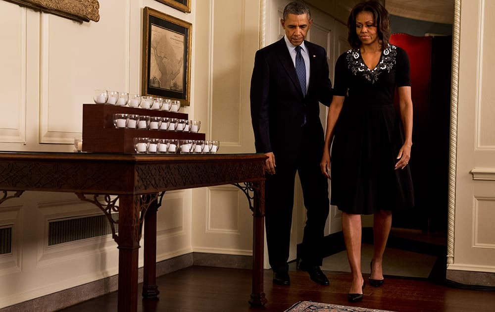 President Barack Obama and first lady Michelle Obama arrive to light twenty-six candles in honor of the Newtown shooting victims, in the Map Room of the White House in Washington.