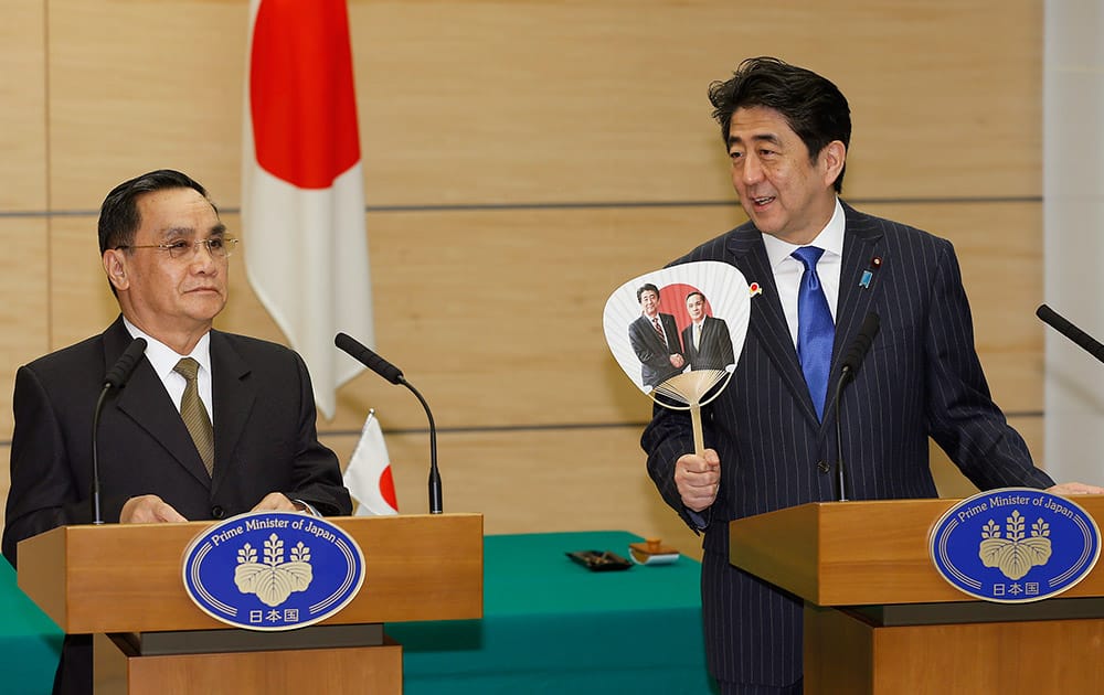 Japanese Prime Minister Shinzo Abe, right, speaks while holding a fan from Laos as Laotian Prime Minister Thongsing Thammavong listens during a joint press conference at Abe`s official residence in Tokyo.
