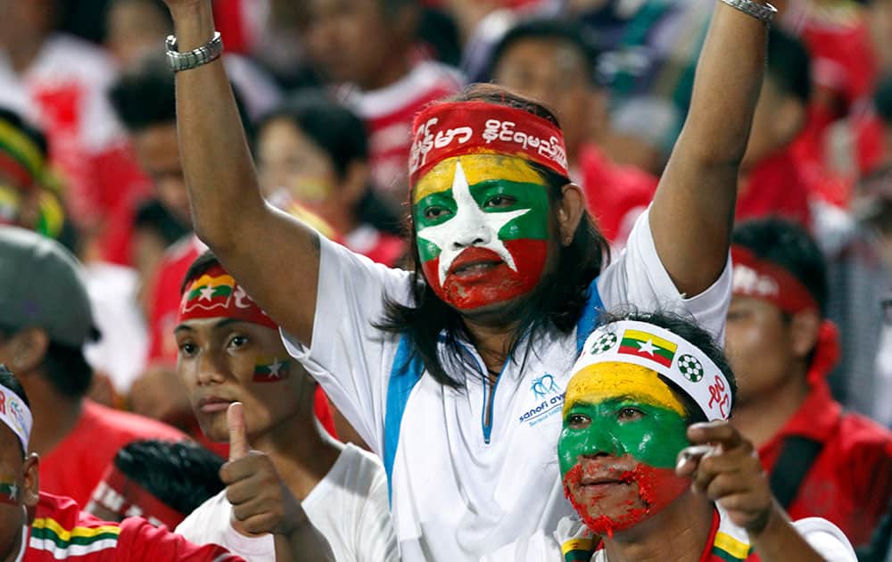 Myanmar soccer fans with their faces painted in the colours of the Myanmar National flag cheer during the soccer match between Myanmar and Thailand in the 27th SEA Games at Thuwunna Stadium in Yangon, Myanmar.