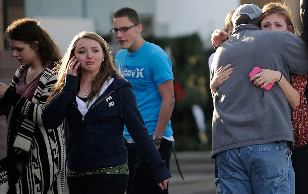 Chris Foster hugs his daughter Devan, after they reunited at the Kings Sooper parking lot of Arapahoe High School after a shooting on the campus in Centennial, Colo.