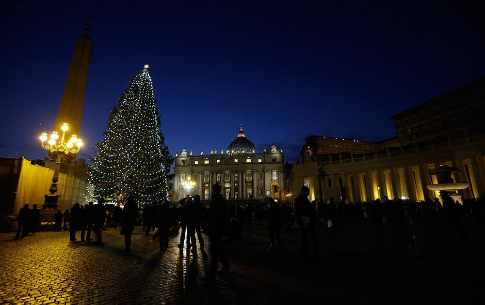 People stop to look at the Christmas tree next to St. Peter`s Basilica in St. Peter`s Square at the Vatican.