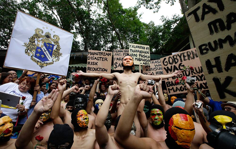 Masked fraternity members from the country`s premier state University of the Philippines, Diliman, display placards during their naked run at their campus at suburban Quezon city, northeast of Manila, Philippines.