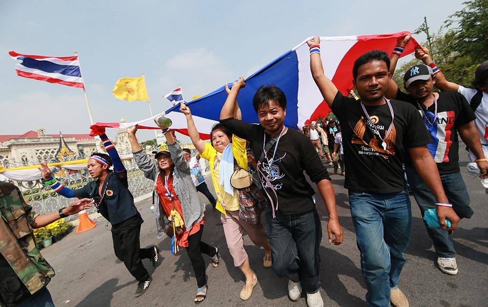 Anti-government protesters carry a long Thai national flag to wrap around the gate and fence around the prime minister`s office, known as Government House, in Bangkok, Thailand.