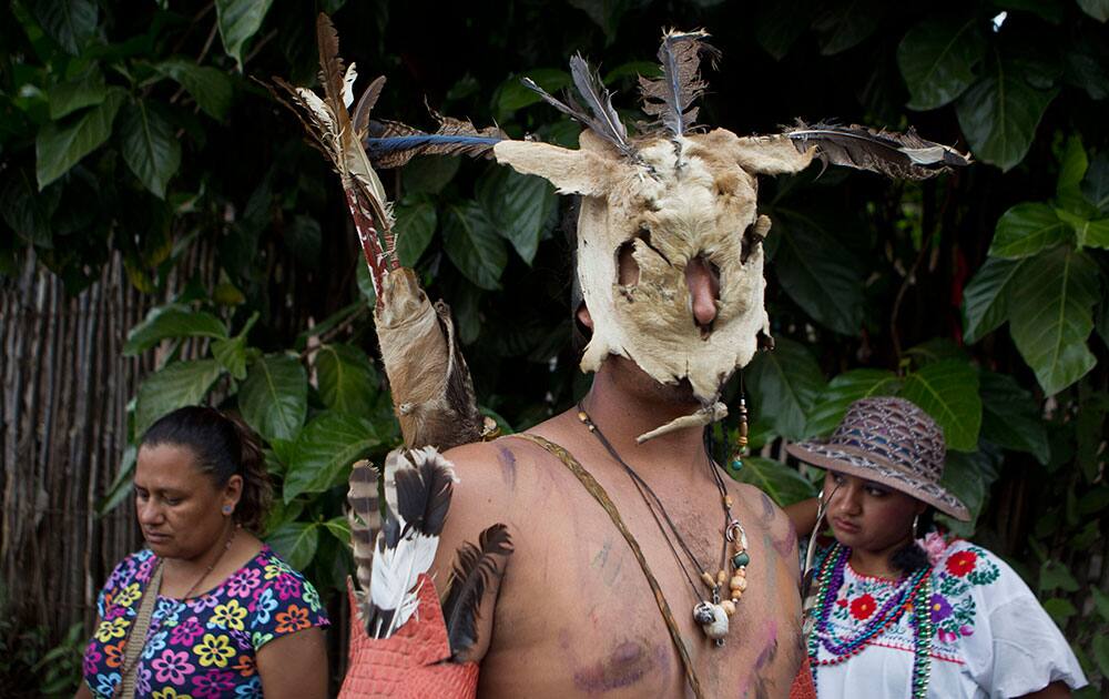 A costumed dancer wearing a mask made out of rabbit fur stands next to women during celebrations in honor of the Virgin of Guadalupe in Condega, Nicaragua.