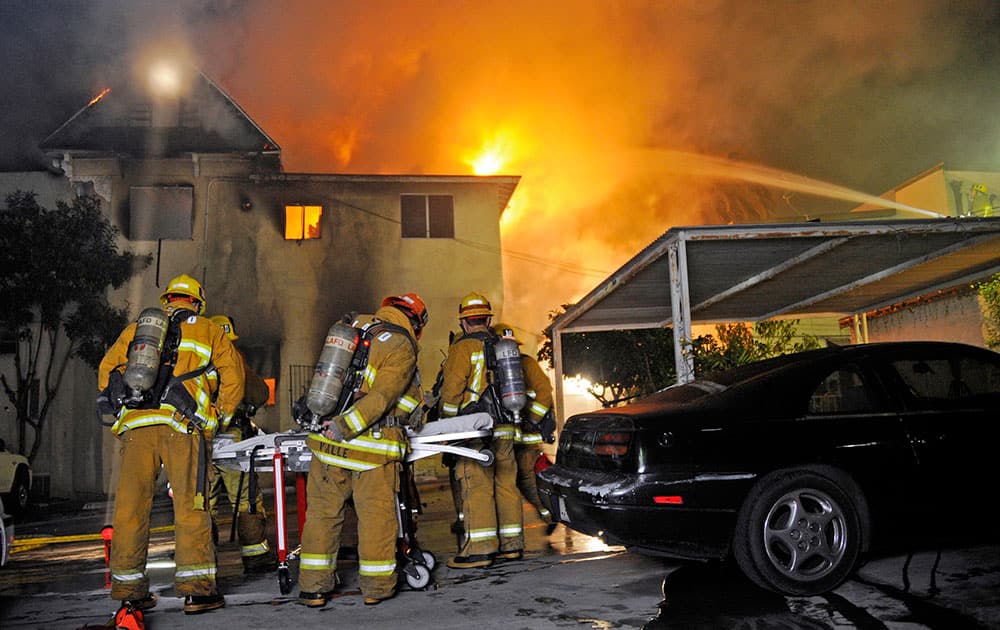 Los Angeles firefighters battle a predawn fire that tore through an apartment building in the Echo Park district, killing two people and injuring three others.