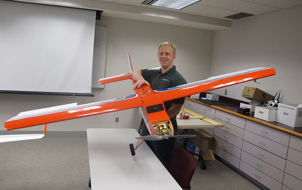 University of North Dakota aviation student Logan Lass lifts a lightweight drone used in training at the Grand Forks, N.D. school`s unmanned aircraft program.