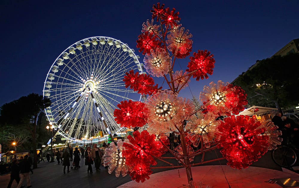 Christmas decorations are displayed in front of a ferris wheel, on a plaza decorated for Christmas in Nice, southeastern France.