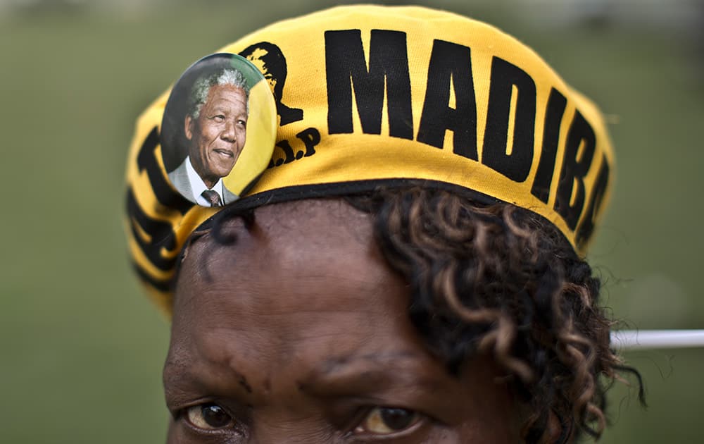 A mourner wearing a badge bearing the image of former President Nelson Mandela, waits with others to go to the Union Buildings where the casket of Nelson Mandela lies in state for three days, in Pretoria, South Africa.